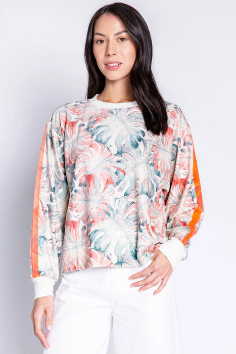 Woman wearing a long sleeve lounge pullover top with tropical leaf print and stripe on the sleeves