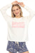 Woman wearing a white fleece pullover lounge top with "Espresso Yourself" pink graphic print at the front