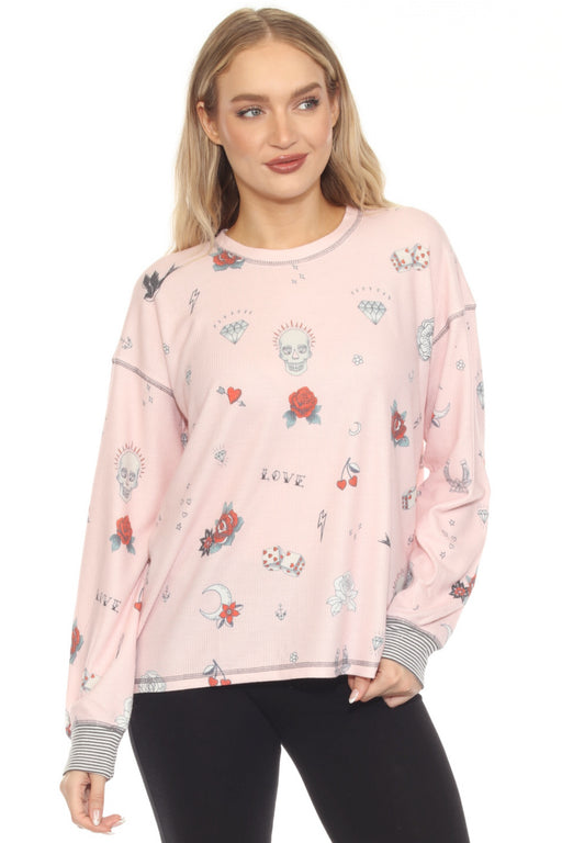 Woman wearing a pink waffle knit top with rock and roll themed print and striped sleeve cuffs