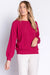 Woman wearing a bright pink sweater knit lounge top with hearts pattern