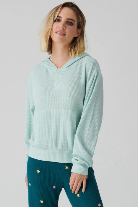Woman wearing a light green solid thermal henley pullover hoodie top with kangaroo pocket and long sleeves