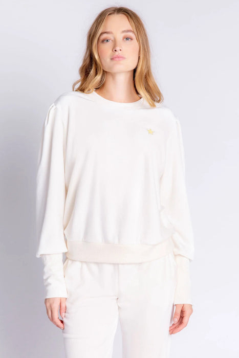 Woman wearing a white lounge pullover top made of velour with small metallic star embroidery